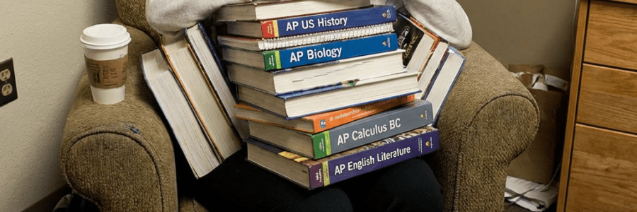 Exhausted student buried under AP US History, Biology, Calculus, and English Literature textbooks.