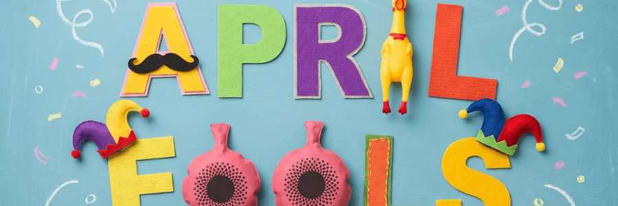 Colorful letters spell Happy April Fools Day with mustaches, jester hats, and rubber chickens.