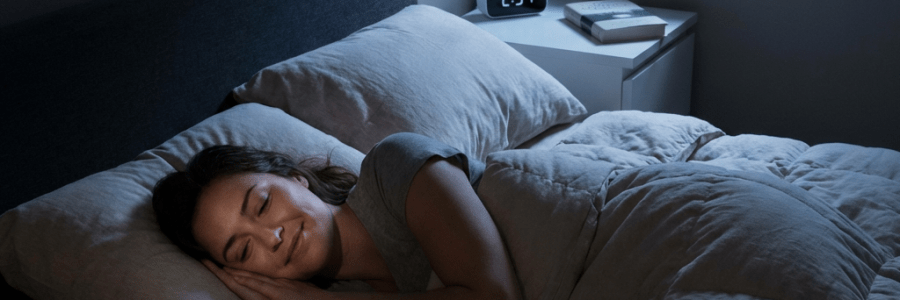 A woman sleeping peacefully in a bed with a digital clock showing 2:37.